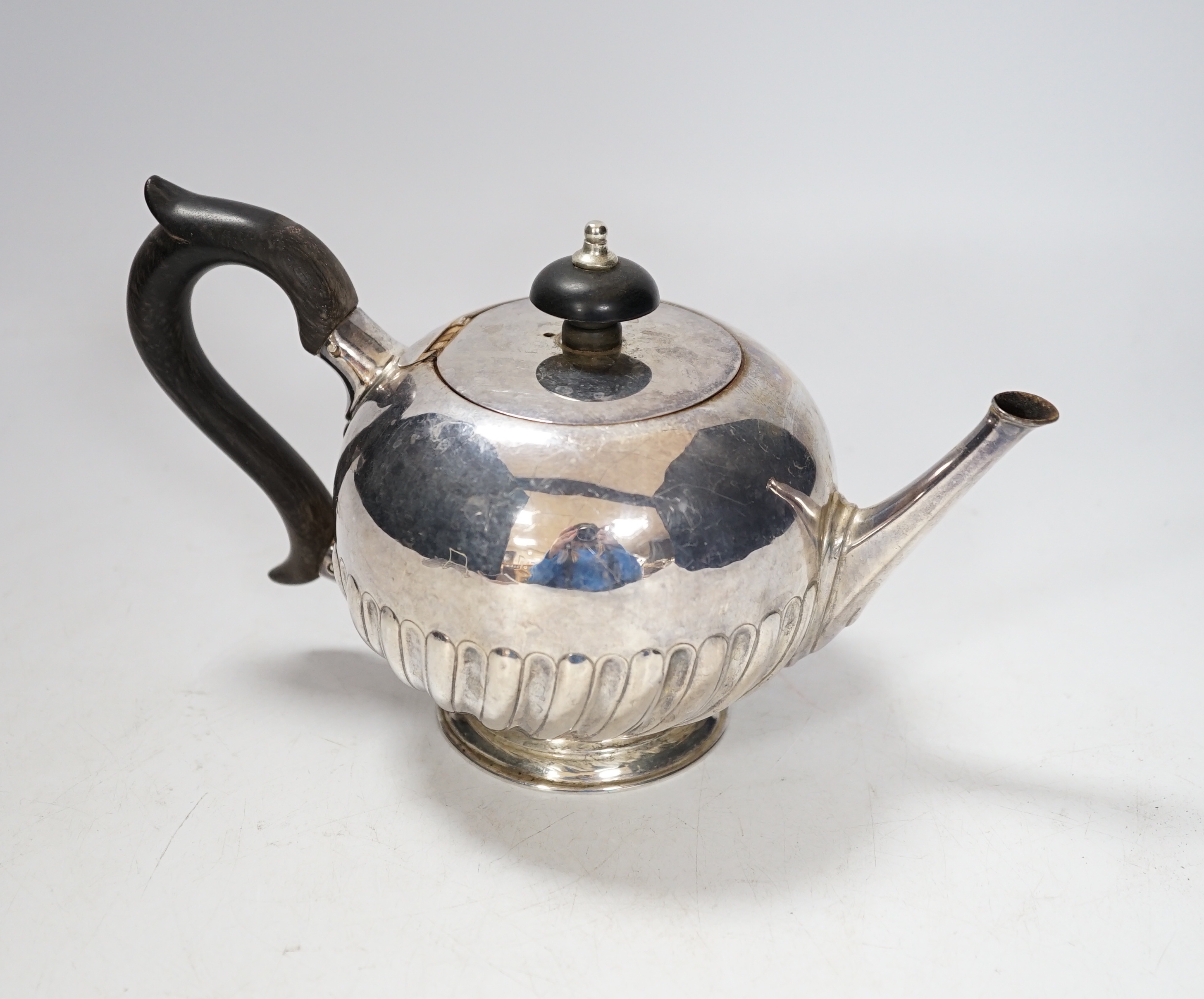A Victorian silver bullet shaped teapot, with ebonised handle and gadrooned body, marks rubbed, London 1895, gross 321 grams